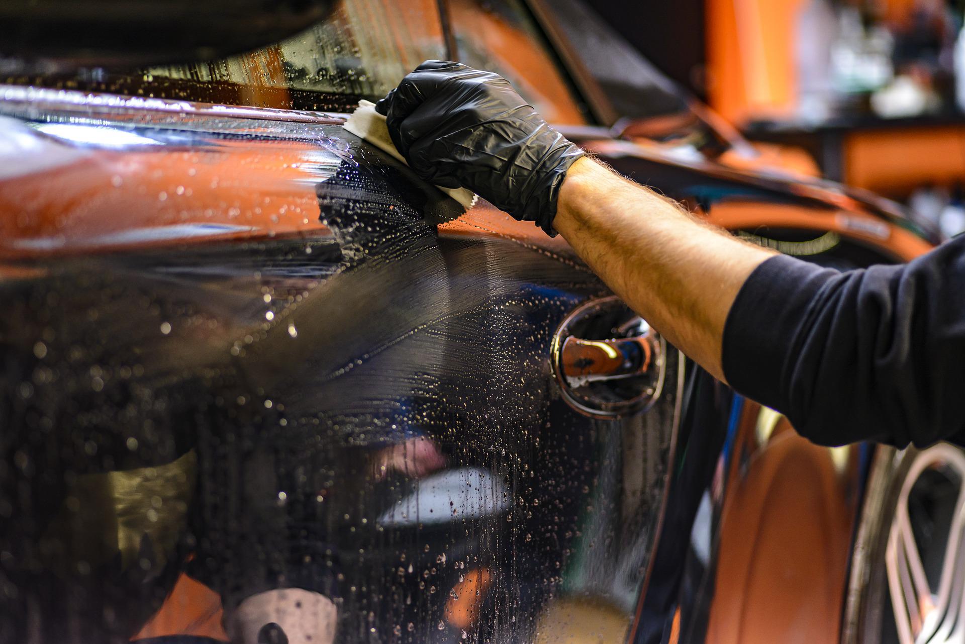 Ruční mytí auta ruka drží hadřík y myje auto