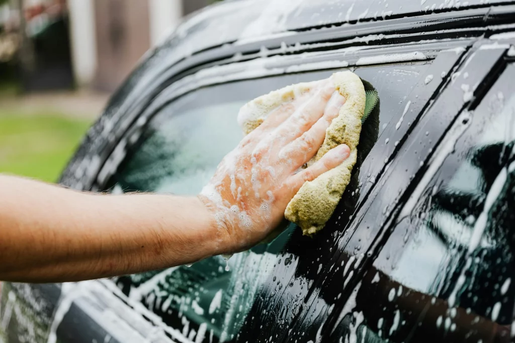 ruční mytí černého auta houbičkou s čistícím prostředkem
